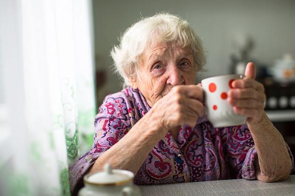 elderly lady drinking tea prepared by care worker